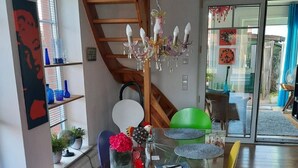 A modern living room with a glass coffee table, red chairs, a wooden staircase, and a chandelier. - Glückstreffer by Interhome (Meppen)