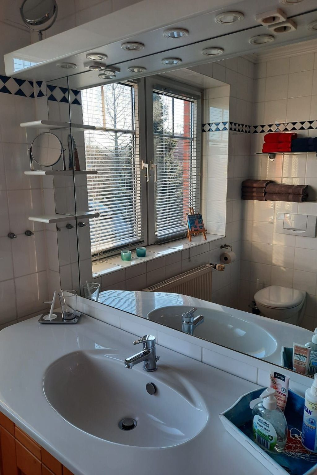 Un baño con dos lavamanos, un espejo y una ventana con persianas.