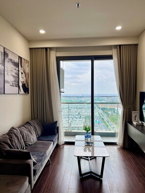 A modern living room with a sofa, a coffee table, and a large window offering a city view. - Sunny Residence (Hanoi)