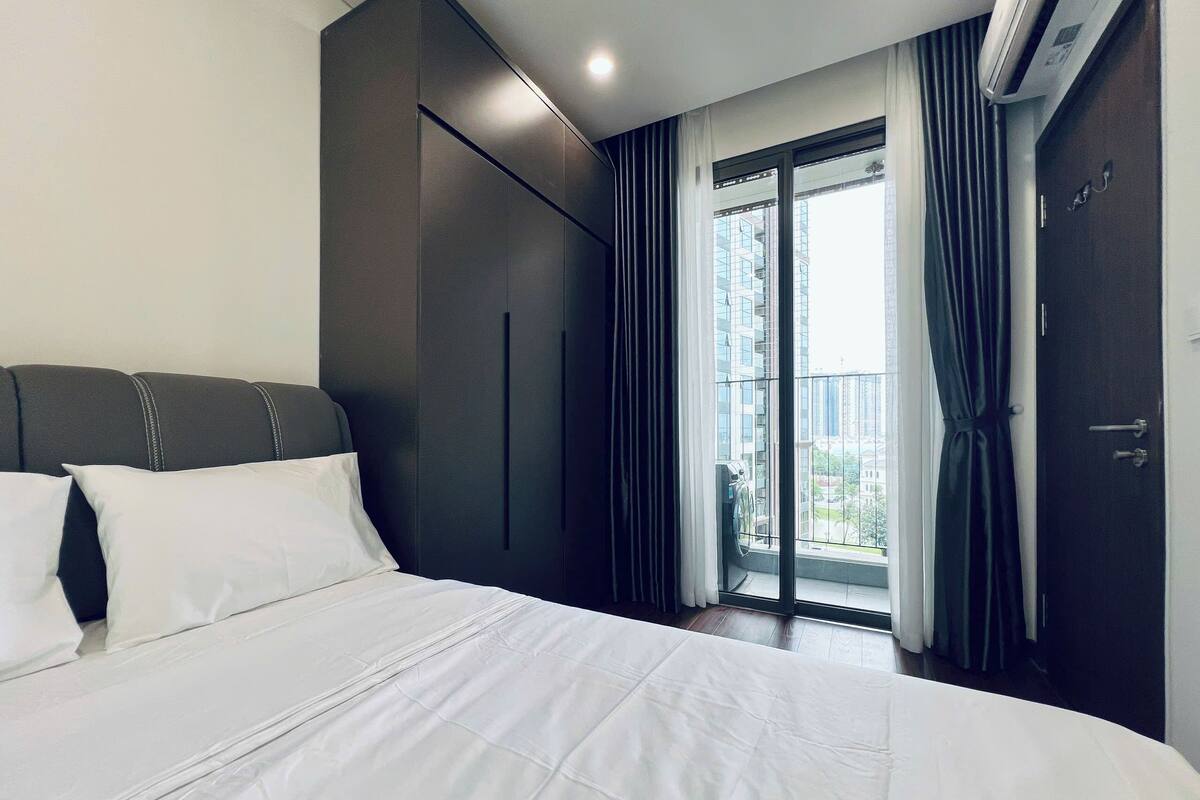 Ein modernes Hotelzimmer mit einem großen Bett, einem Kleiderschrank und einem Balkon mit Vorhängen.