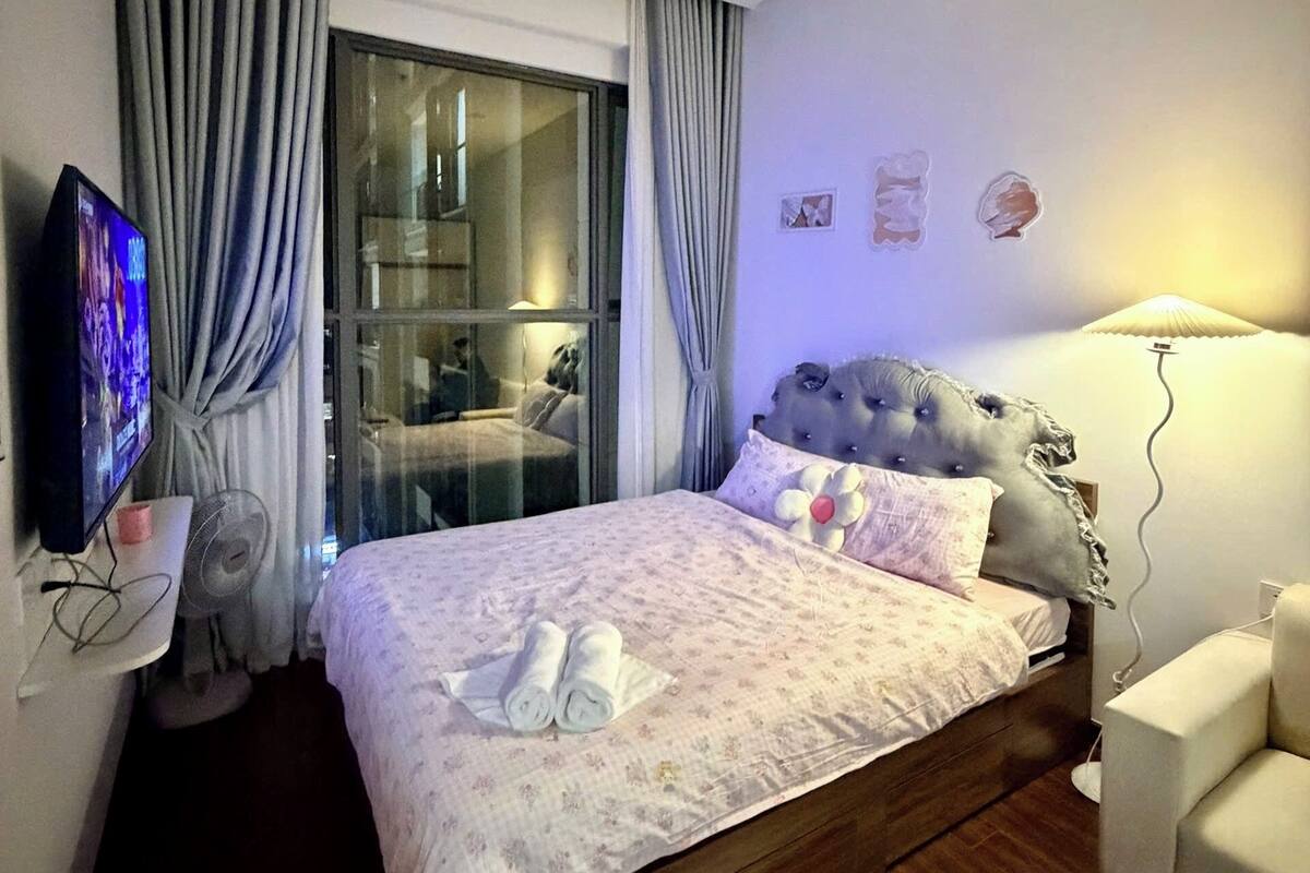 Ein Hotelzimmer mit Bett, Fernseher, Ventilator, Stuhl und einem Fenster mit Vorhängen.