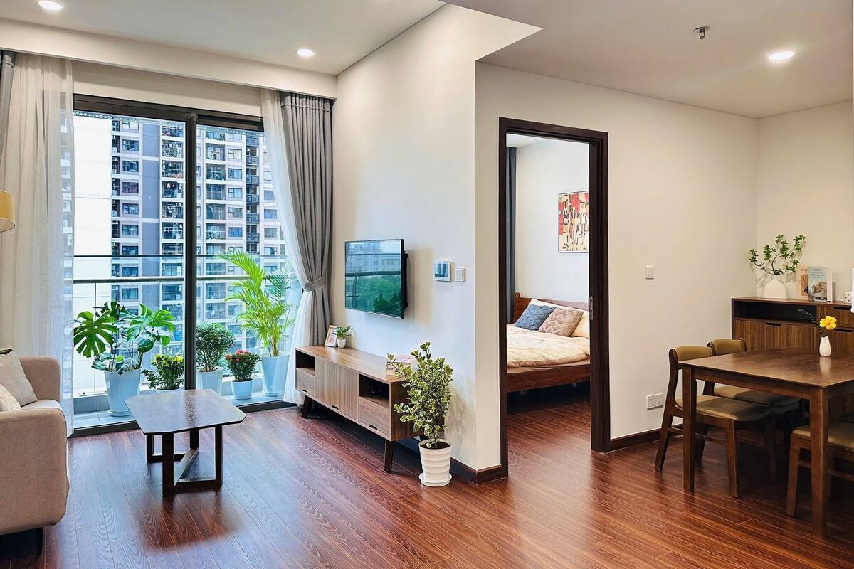 Ein modernes Apartment mit großem Fenster, Flachbildfernseher, Essbereich und einem Bett.