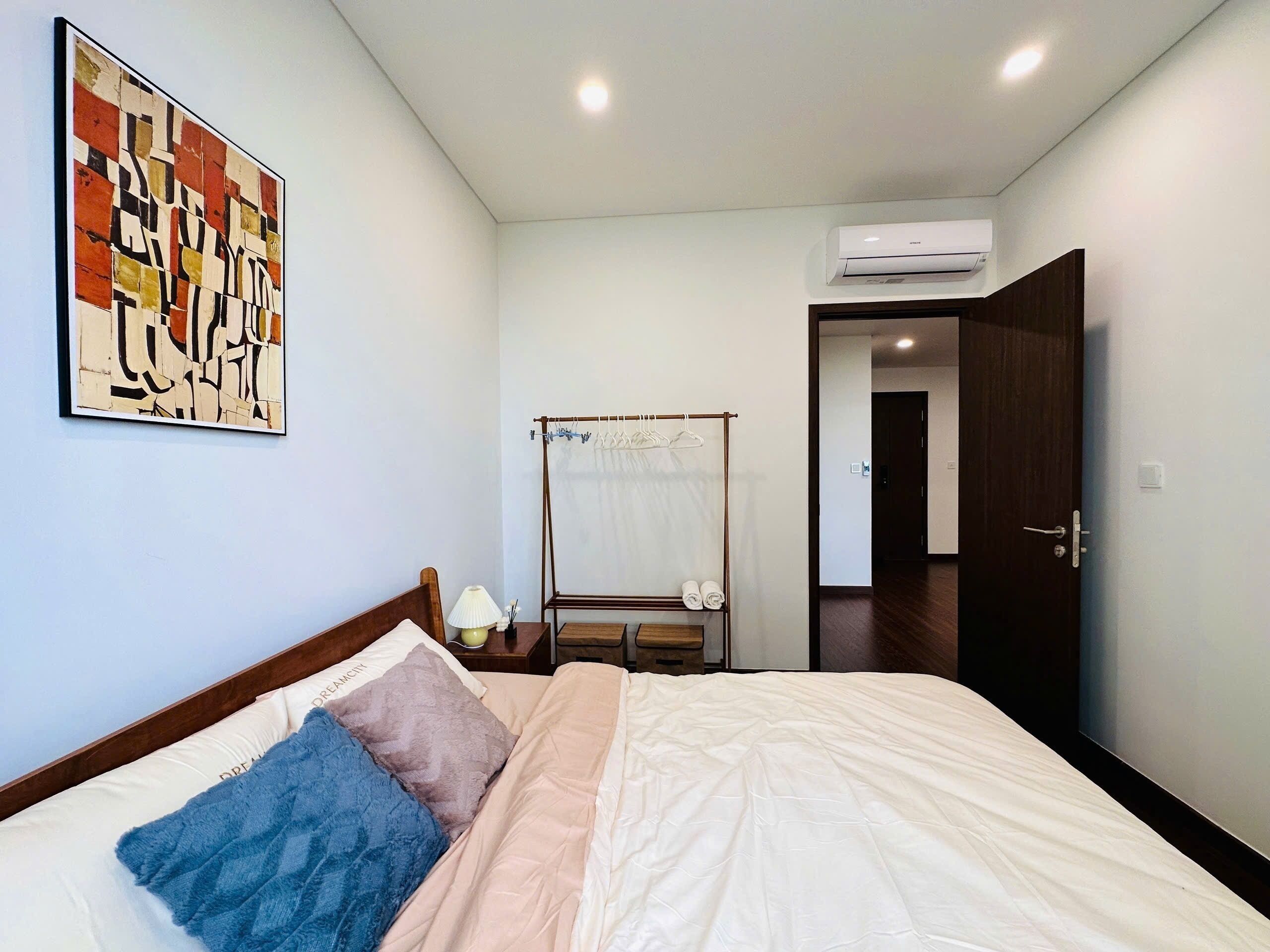 A bedroom with a bed, a wall-mounted air conditioner, a door, and a hallway.