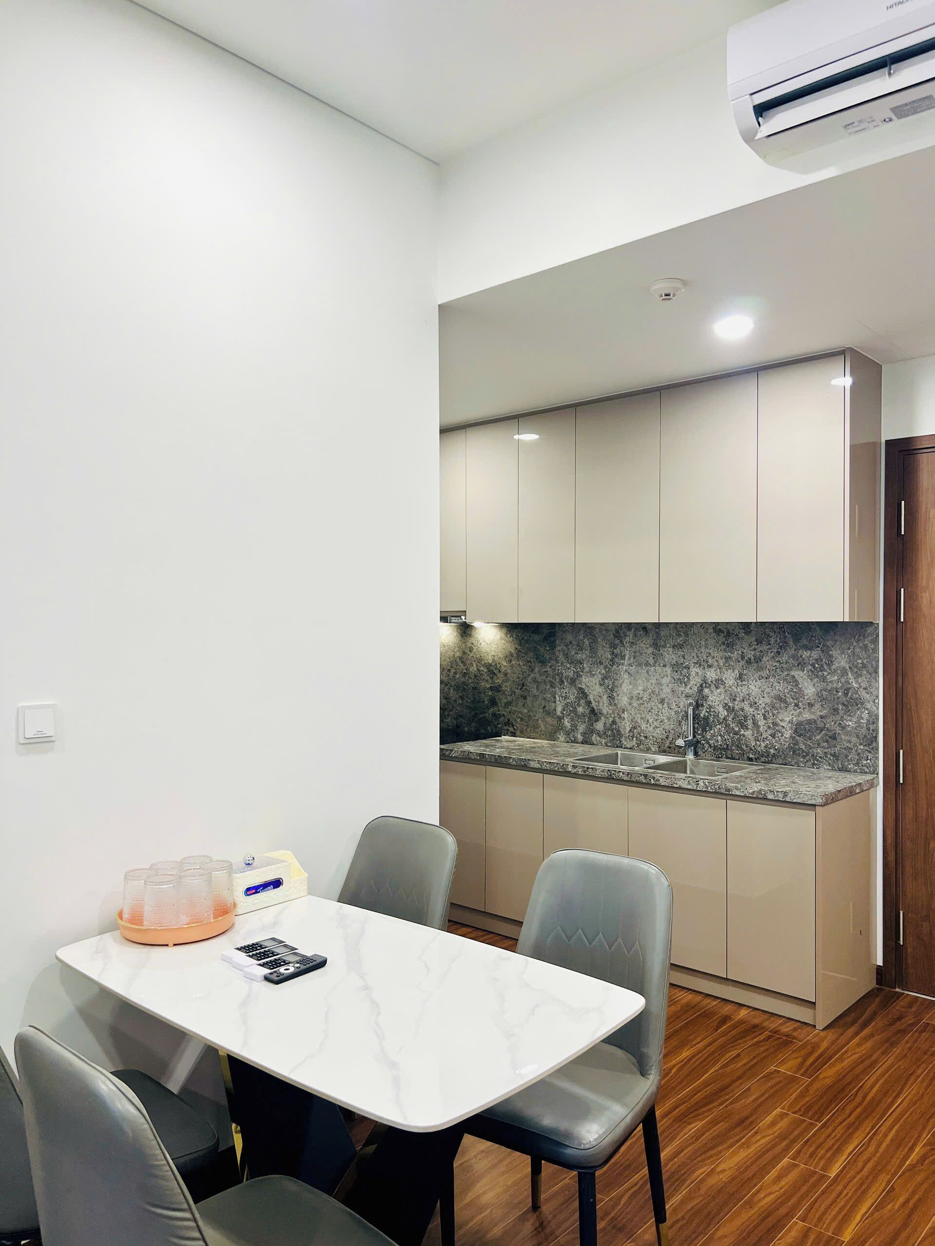A modern kitchen with a marble countertop, built-in cabinets, and a wooden floor.