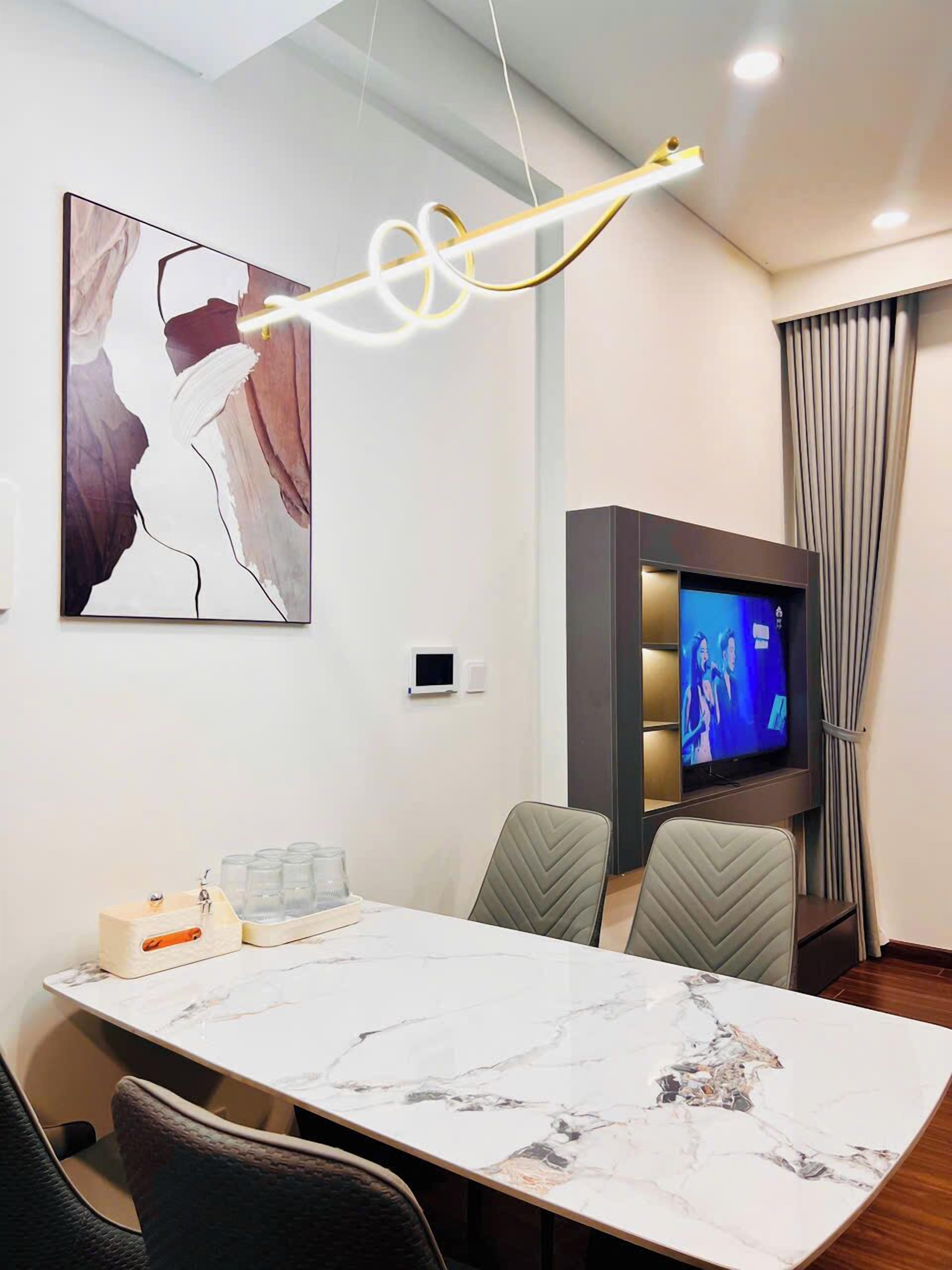 Una moderna camera d'albergo con un tavolo da pranzo in marmo, comode sedie, una TV a schermo piatto e un'opera d'arte contemporanea appesa al muro.