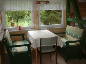 A room with a table and two chairs, a window with a view of greenery, and a ladder against the wall. - in Neustadt/Harz mit Grill by Interhome (Niedersachswerfen)