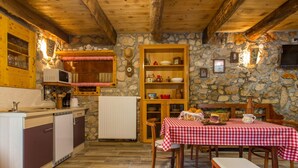 A rustic kitchen with wooden beams, stone walls, and a checkered tablecloth-covered table. - Gemütliches Steinhaus Nonna Stara by Interhome (Polje)