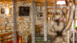 A rustic stone-walled room with a wooden table, a vintage trunk, and shelves with kitchenware. - Gemütliches Steinhaus Nonna Stara by Interhome (Polje)