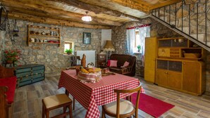 A rustic dining area with a checkered tablecloth, wooden chairs, and a stone wall. - Gemütliches Steinhaus Nonna Stara by Interhome (Polje)