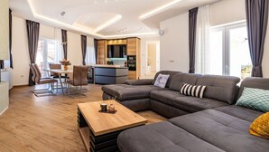 A modern living room with a sectional sofa, a wooden coffee table, and a dining area with a table and chairs.