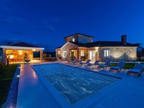 Una casa de piedra con piscina y sillas de descanso.