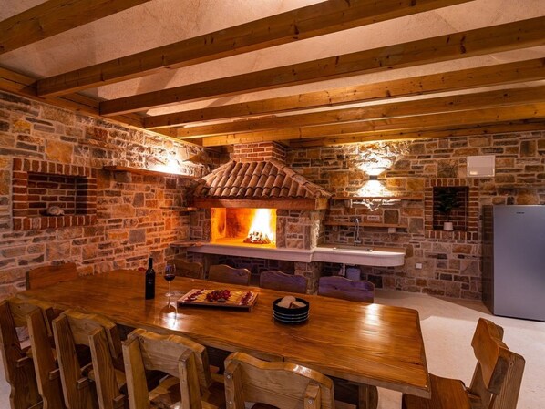 Una cocina rústica de piedra con estufa de leña, una mesa de comedor y sillas.