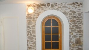 Un mur de pierre avec une porte en bois et un luminaire au-dessus.