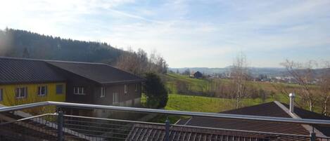 A residential area with houses, a clear sky, and a hilly landscape in the background.