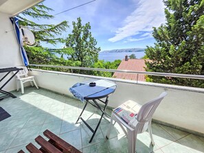Ein Balkon mit Tisch, Stühlen und Meerblick.
