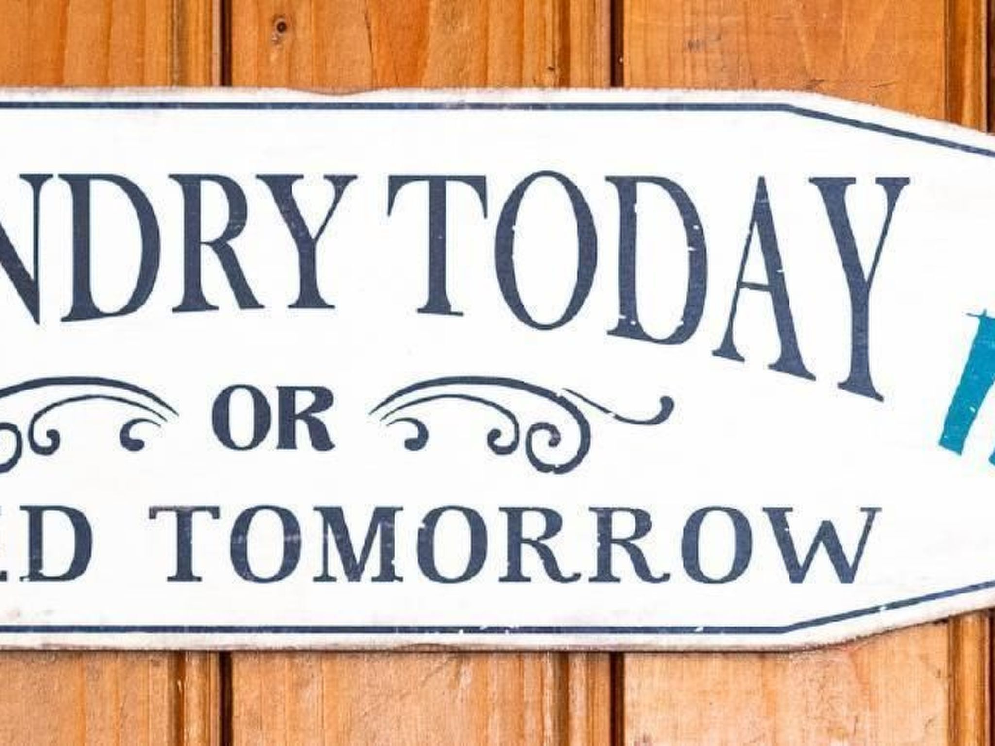 A sign with the text "DRY TODAY OR DRAIN TOMORROW" on a white background with a blue border, mounted on a wooden surface.