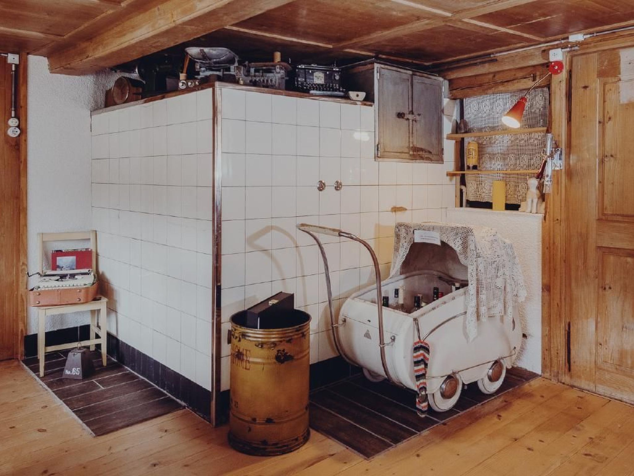 A compact kitchen with white tiles, a vintage washing machine, and a wooden floor.