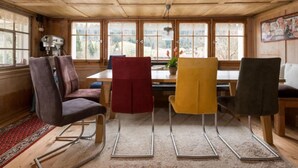 A wooden interior with a dining table, four chairs, and large windows. - Lindeli by Interhome (St. Peterzell)