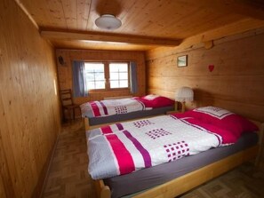 Een houten hutje met twee bedden, een raam en een plafondlamp.