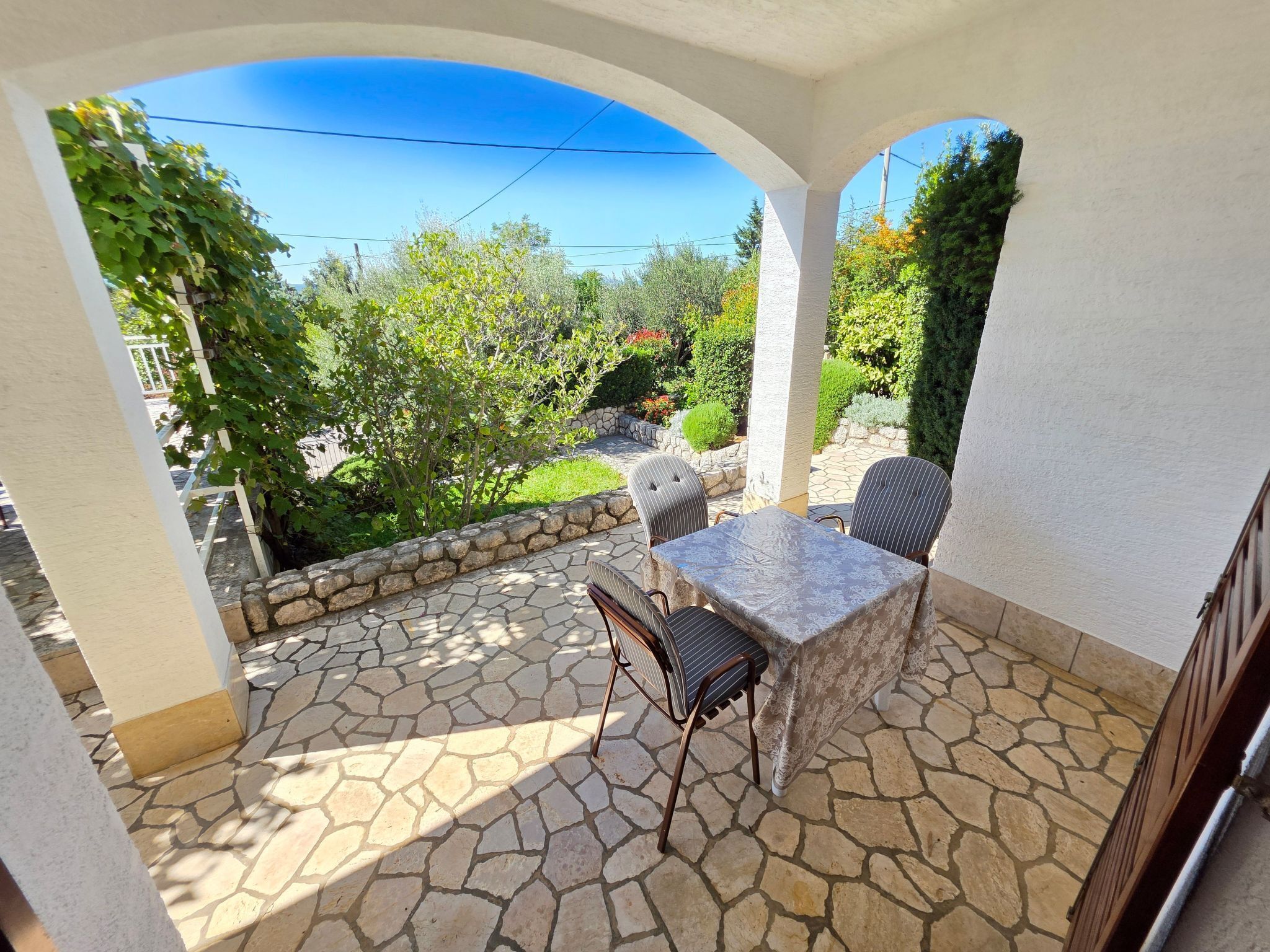 A patio with stone flooring, a table, and two chairs.