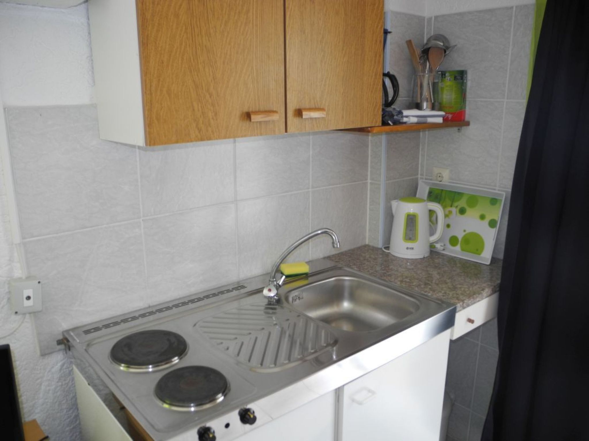A compact kitchen with a built-in stove, a sink, and wooden cabinets.