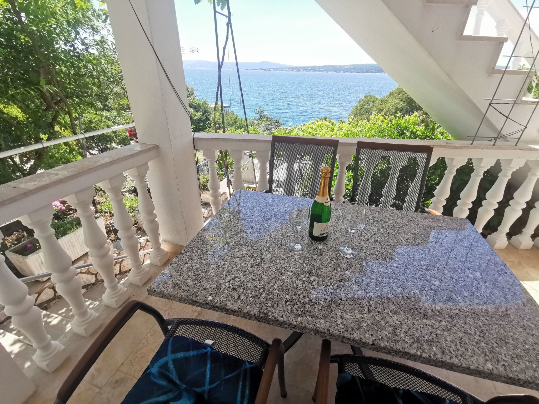 A balcony with a table, chairs, and a bottle of champagne.
