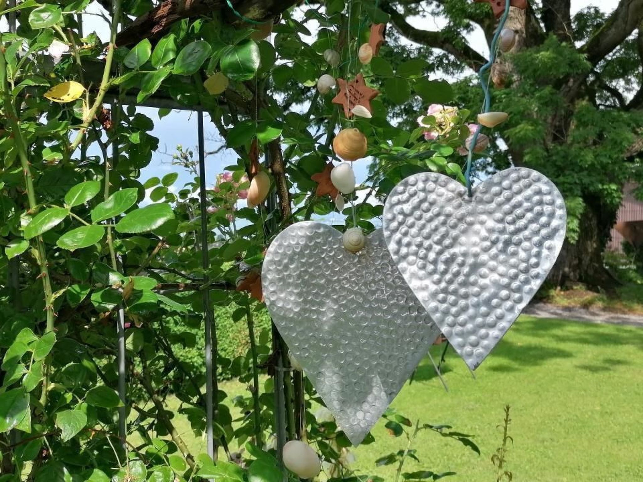 Due decorazioni a forma di cuore appese a un ramo.