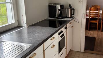 Een koelkast, een oven, kookgerei, borden en bestek