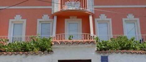 A building with a balcony, a door marked with the number 10, and a clear sky.