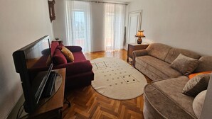Ein Wohnzimmer mit Fernseher, zwei Sofas, einem Teppich und einer Lampe.