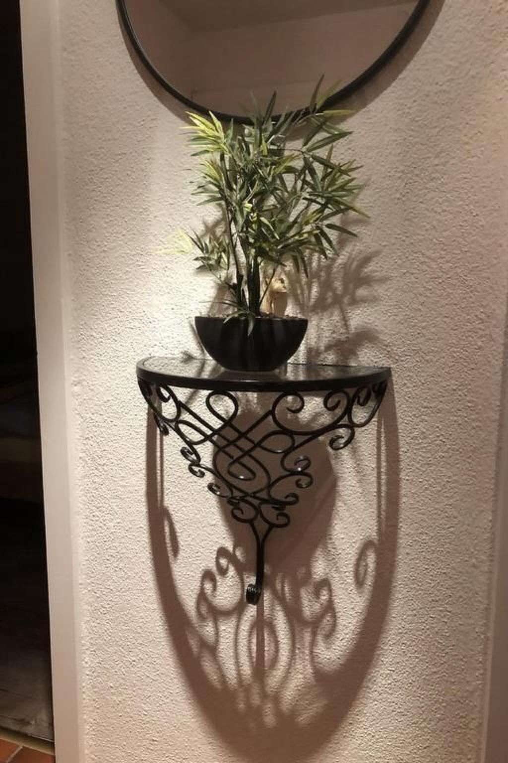 A potted plant on a wall-mounted shelf with a decorative metal design.