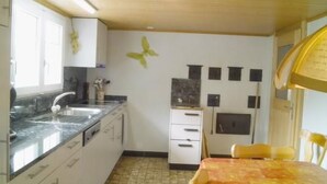 Eine kleine Küche mit Spüle, Arbeitsfläche und einem Essbereich mit Tisch und Stühlen.