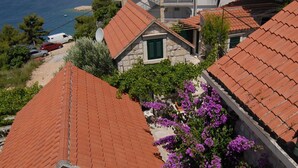 Ett bostadsområde vid kusten med hus som har tak av terrakottafärgat tegel, en gångstig av sten och utsikt över havet.