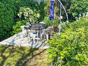 A patio with a table and chairs, surrounded by lush greenery and a pergola with a blue umbrella. - HAUS 3 SCHLAFZIMMER 3 BÄDER by Interhome (Beaumont en Véron)