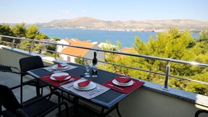 Een balkon met een tafeltje voor twee, met uitzicht op de kust en bergen in de verte.