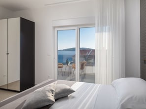 Ein modernes Schlafzimmer mit einem großen Bett, einem Kleiderschrank und einem Balkon mit Meerblick.