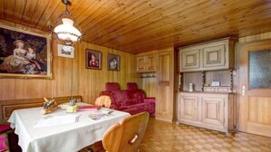 Un interior de fusta amb una taula de dinar, cadires, un sofà vermell i una zona de cuina amb armaris.