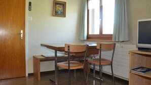 A compact room with a desk, two chairs, a television, and a window with curtains. - Sutter in Brülisau bei Appenzell by Interhome (Brülisau)