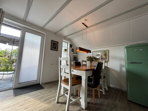 Ein Essbereich mit Tisch, Stühlen und einem grünen Kühlschrank.