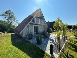 A house with a sloped roof, a patio with outdoor furniture, and a fenced yard. - Haus Kormoran am Lauwersmeer by Interhome (Anjum)