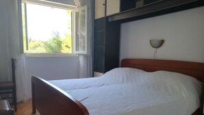 Un dormitorio con una cama de madera, una ventana con cortinas y una lámpara de pared.