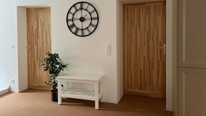 A hallway with a white bench, a wall clock, and wooden doors. - South Beach Apartment 10km Rheinfall by Interhome (Hemmental)