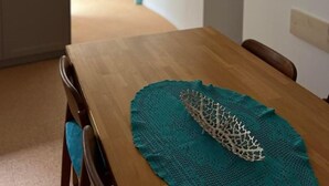 A dining area with a wooden table, teal placemat, and hanging glass bottles. - South Beach Apartment 10km Rheinfall by Interhome (Hemmental)
