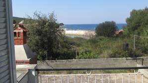 Un balcon avec vue sur la mer et une plage éloignée.
