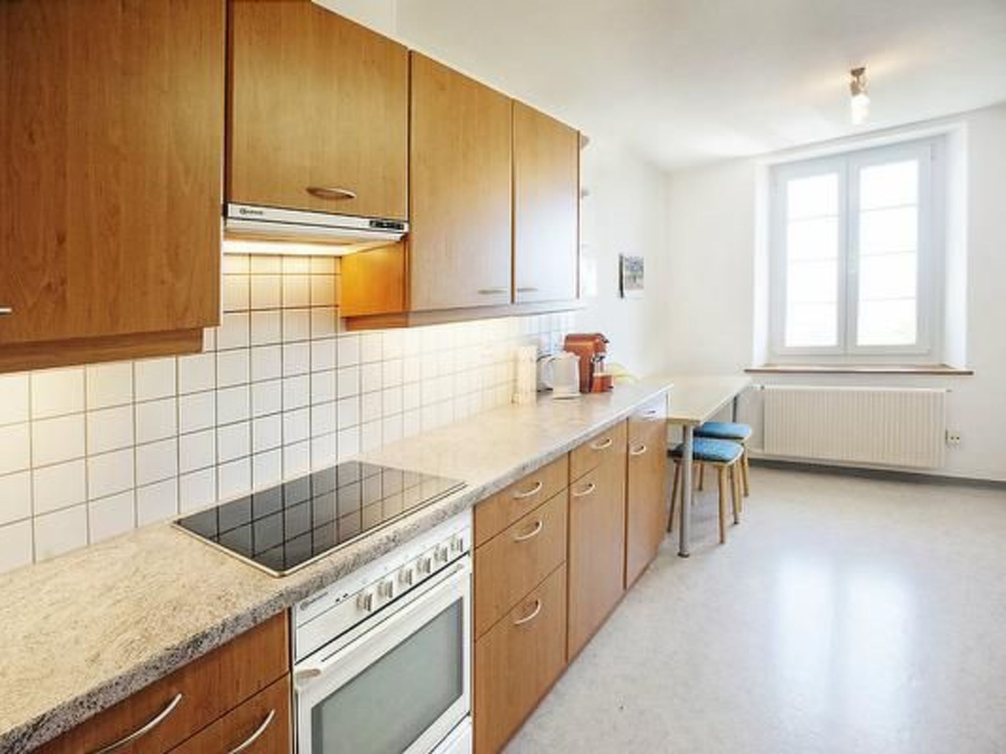 Una cocina con armarios de madera, horno empotrado, placa de cocina y una ventana que proporciona luz natural.