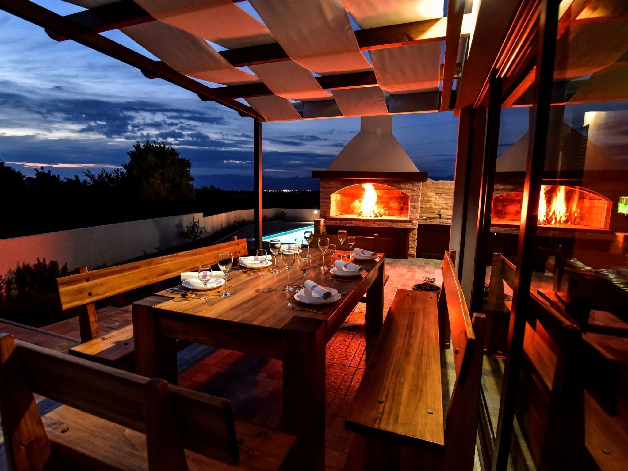 Un espace extérieur aménagé pour les repas, avec un four en briques et une vue sur le ciel.