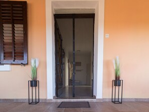 A hotel entrance with a glass door, two potted plants, and a tiled floor. - "Jasmin" by Interhome (Nin)