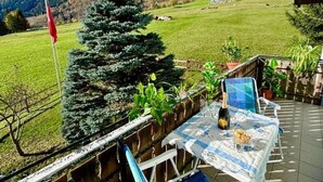 Un patio con mesa lista para dos personas, con vista a un paisaje montañoso.