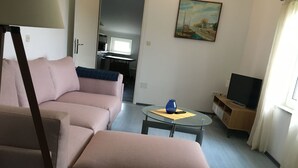 A living room with a sofa, a coffee table, a TV stand, and a painting on the wall. - The Blue Line Ferienwohnung mit Balkon by Interhome (Rab/Kampor)