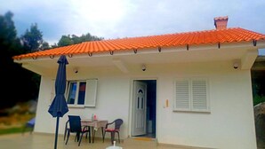 A single-story house with a red-tiled roof, a small patio with a table and chairs, and a blue umbrella. - "Waldhaus" in der Nähe des Strandes by Interhome (Rab/Kampor)